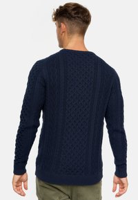 granatowy sweter robiony na drutach z wzorem w warkocze, okrągły dekolt, ściągacze na mankietach i na dole, fakturowane wykończenie, dopasowany krój.