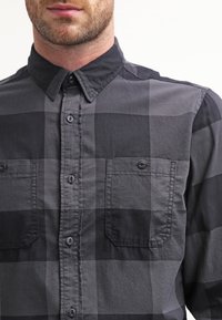 Langärmliges kariertes Hemd in Schwarz- und Grautönen, mit durchgehender Knopfleiste, zwei Brusttaschen und klassischem Kragen.