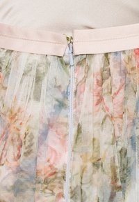 Bloemen tule rok met een roze satijnen tailleband en een verborgen rits aan de achterkant, met zachte pasteltinten en een transparante textuur.