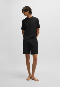 Ensemble composé d'un t-shirt à manches courtes noir et d'un short, fabriqué dans un tissu texturé avec un logo de marque discret sur le t-shirt, offrant une coupe décontractée.