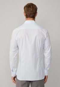 Hellblau kariertes Hemd aus Baumwolle, mit langen Ärmeln, knöpfbaren Manschetten und einem klassischen Kragen. Sanfte Textur mit taillierter Passform.