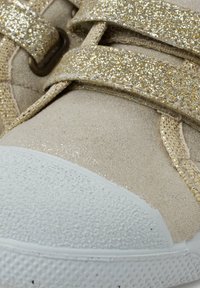 Beżowe sneakersy z błyszczącymi złotymi paseczkami, teksturowana zamszowa cholewka, biała gumowa podeszwa oraz wzmocniony czubek. błyszczące akcenty podkreślają design.