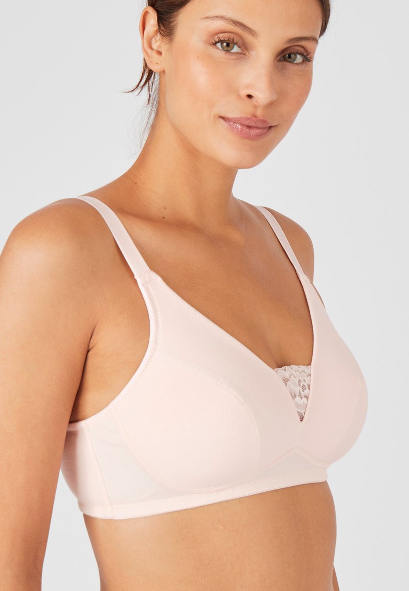 Reggiseno rosa chiaro in tessuto morbido, con bordo in pizzo sul collo, spalline regolabili e design della coppa senza cuciture e sagomato.