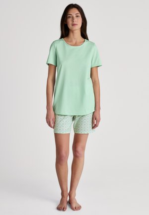 T-shirt verde menta con maniche corte abbinata a pantaloni corti verde menta a fantasia con disegni floreali in colori chiari. Tessuto morbido e leggero.