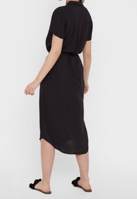 Black midi dress with short sleeves, collar, and cinched waist. Features a flowing silhouette and a slightly asymmetric hemline.