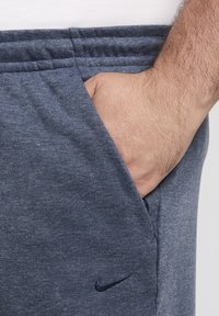 Pantalones deportivos Nike de tela de jersey azul oscuro, con banda elástica en la cintura, bolsillo lateral y logo bordado en color marino.