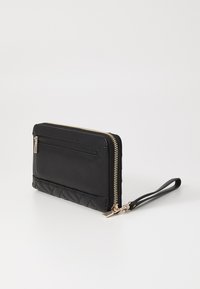 Portafoglio in pelle nera con texture trapuntata, zip dorata e tracolla. Presenta una tasca zip frontale e un design minimalista.