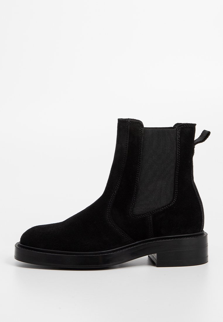 Stivale Chelsea in suede nero con pannelli laterali elasticizzati, linguetta, punta rotonda e suola nera spessa. Presenta una texture liscia e un design minimale.