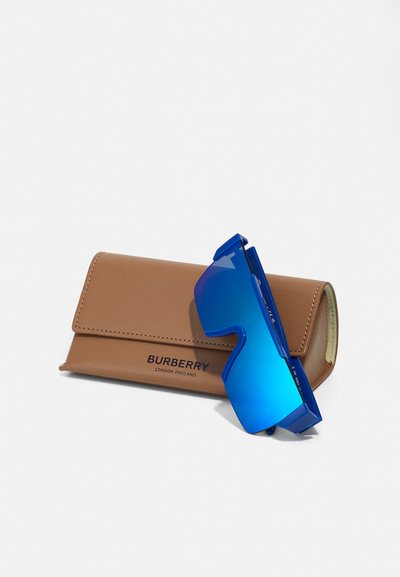 Blaue Sonnenbrille mit einem markanten, kantigen Design neben einer braunen Lederhülle mit geprägtem "BURBERRY"-Logo.