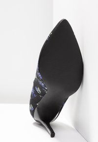 Chaussure à talon haut à bout pointu avec une tige en tissu noir ornée de motifs floraux bleus et verts. Talon noir fin et semelle texturée.