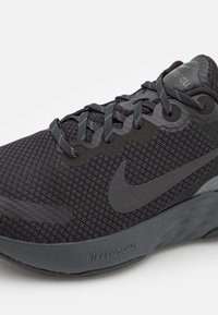 Baskets noires de sport avec un dessus en maille, des accents texturés et des lacets plats. Présente un logo Nike noir bien visible et la marque "NIKE RENEW" sur la semelle.