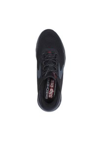 Chaussure de sport noire avec un dessus en mesh, accents gris et une étiquette rouge portant la mention "SKECHERS slip-ins." Présente un design profil bas, enfilable.