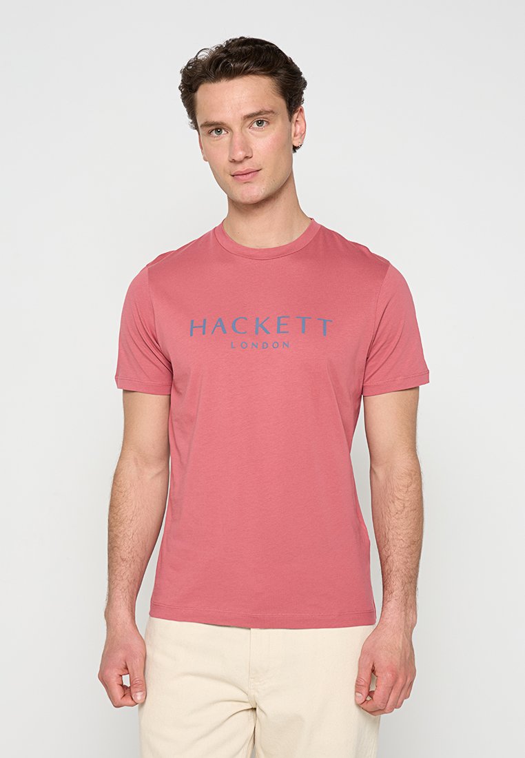 T-shirt en coton rose foncé à manches courtes, arborant un logo bleu "HACKETT LONDON" sur le devant. Design simple avec col rond.