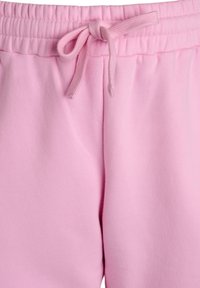 Pantalones de chándal rosa claro con cinturilla elástica y cordón, textura suave y costuras sutiles alrededor de las uniones.