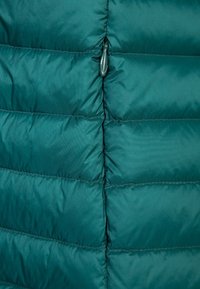 Turkusowa kurtka puchowa z pikowanym wzorem, poziomymi kanałami, przednim zamkiem błyskawicznym oraz gładką, lekko błyszczącą teksturą materiału.