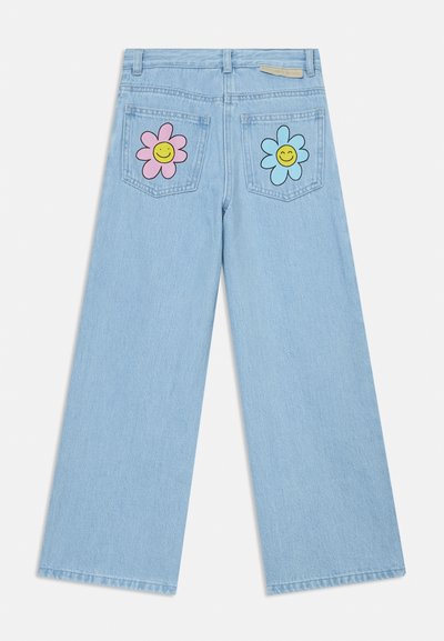 Jeans de ganga de perna larga em azul claro com desenhos de flores e sorrisos em rosa e azul nos bolsos traseiros. Textura desgastada no tecido.