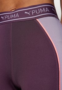 Vijolične legging hlače z logotipom PUMA na pasu, ki imajo kontrastno roza stransko črto in gladko, elastično blago za udobje in prožnost.