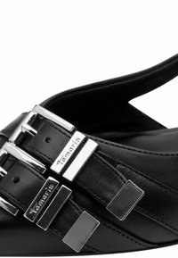 Juodos odinės sandalės su sidabriniais metaliniais akcentais ir keliais sagties dirželiais. Paviršius lygus, dizainas minimalus.