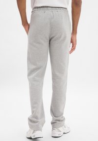 Grijze, casual sweatpants met een elastische tailleband, zijzakken en een recht gesneden pijp, gecombineerd met witte sportschoenen.