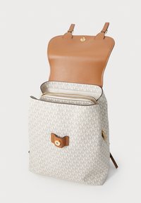 Rugzak met een beige canvas buitenzijde met een totaal logo patroon, een bruine leren klep, gouden hardware en een interne ritszak.