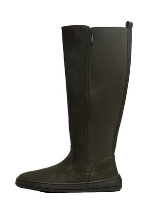 Bota alta marrón oscuro con suela negra plana y panel elástico en la parte trasera para fácil uso, vista de lado sobre fondo blanco.