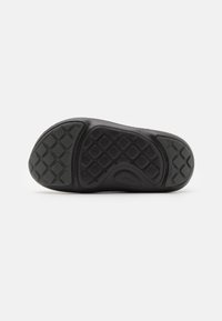 Svart gummisula med texturerat greppmönster, med upphöjda diamantskivor och cirkulära detaljer för bättre grepp.