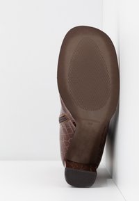 Bottine marron en cuir texturé à motif croco avec une fermeture éclair sur le côté. Semelle plate en caoutchouc avec motifs antidérapants. Taille 38, fabriquée en Espagne.