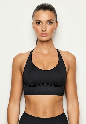Soutien-gorge de sport noir avec un décolleté en forme de scoop, design dos nageur et texture lisse. Le tissu est élastique avec des détails de coutures minimes.