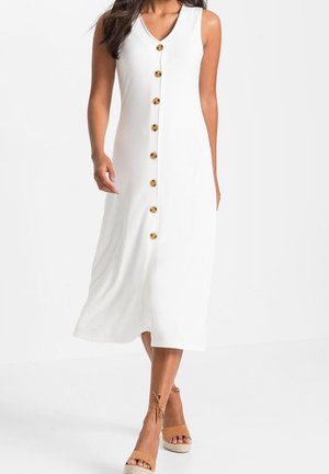 Vestido midi blanco sin mangas con botones delanteros de carey, escote en V, combinado con sandalias cuña de esparto color beige con lazada en el tobillo.