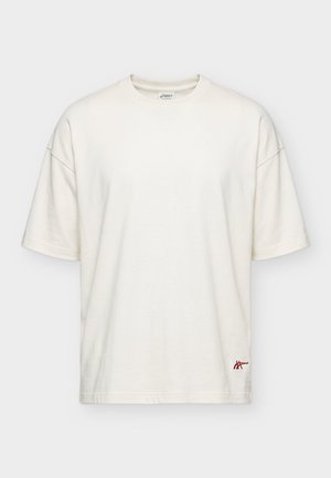 Mand med vådt hår iført hvid T-shirt med teksten "Run in Chicago" og billede af pizza på ryggen, kombineret med sorte shorts.