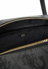 Intérieur d'un sac à main en simili cuir noir avec une fermeture éclair, présentant une texture lisse, une doublure en tissu noir et un motif logo subtil.