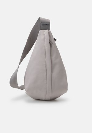 Jasnoszara, kroplowata torebka na ramię z szerokim regulowanym paskiem i logo Calvin Klein w górnym rogu.