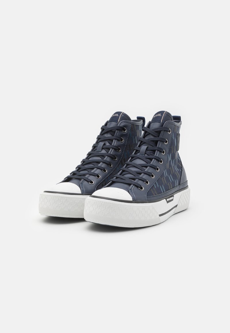 Baskets montantes en cuir bleu marine avec un côté à motifs, bout en caoutchouc blanc et semelle extérieure texturée blanche, avec des accents noirs.