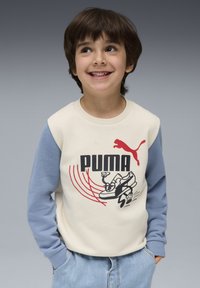 Sudadera Puma con un cuerpo color crema, mangas azules y un atrevido estampado gráfico de zapatos y logotipo. Textura suave, ajuste casual.