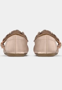 Chaussures plates rose blush avec des embellissements floraux, une texture satinée lisse, un bout rond et un petit talon, avec une fermeture à boucle simple.