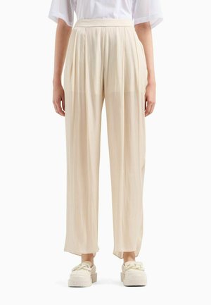 Pantaloni a palazzo plissettati in tessuto beige chiaro, con vita alta e spacchi laterali, abbinati a sneaker beige in piattaforma texturizzate.