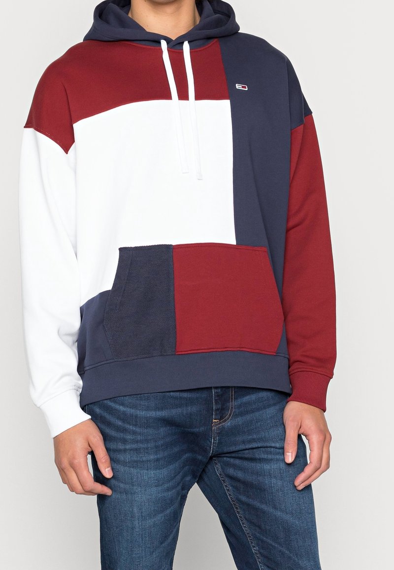 Kapuzenpullover mit Farbblockierung in Marineblau, Weiß und Bordeaux. Verfügt über eine Kängurutasche und Zugbänder. Gerippte Bündchen und Saum.