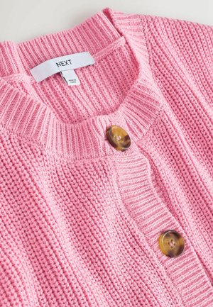 Lyserød strikket cardigan med ribbet struktur, rund halsudskæring og to store brune knapper foran. Etiketten siger "NEXT."
