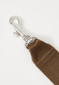 Brun tygrem med en metallisk silverklämma och ringkoppling, med tajt sömnad längs kanten.
