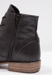 Bottine en cuir noir avec fermeture éclair latérale, lacets sur le devant et talon en bois superposé.