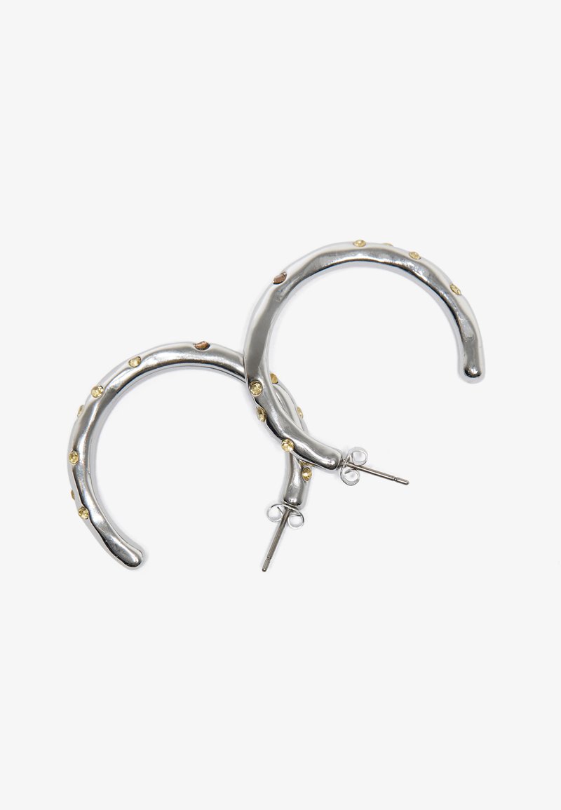 Sølv hoop øreringer med en polert finish, som har små gyldne detaljer og et teksturert, bølgete design. Bakgrunns lukking.