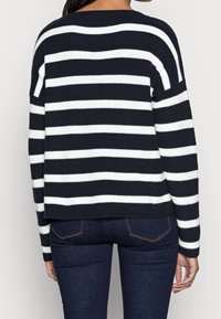 Námořnický modrý a bílý pruhovaný pletený svetr s uvolněným střihem, ribbed texturou a spadlými rameny. Zobrazený ze zadní strany s cropped siluetou.