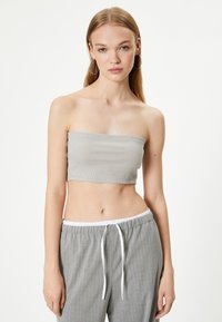 Top bandeau gris de canalé combinado con pantalones gris a rayas. La tela parece suave con una textura lisa, presentando un diseño ajustado.