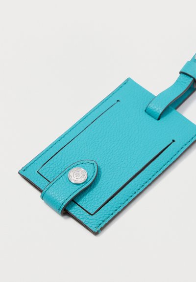 Eticheta de bagaj din piele turcoaz, cu un finisaj texturat, având cusături negre, închidere cu buton și o curea pentru atașare.