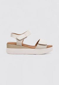 Sandalias de color beige claro con parte superior texturizada, doble correa de Velcro y suela con plataforma que presenta una base crema y una plantilla marrón.