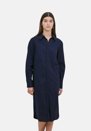 Vestido camisas azul marino con botones, de manga larga, cuello y bolsillo en el pecho. Tejido suave, hasta la rodilla, con corte recto y una sutil abertura en el dobladillo.