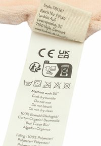 Label tag with care instructions. Soft, light pink fabric, 100% organic cotton. Contains washing symbols and text in multiple languages.