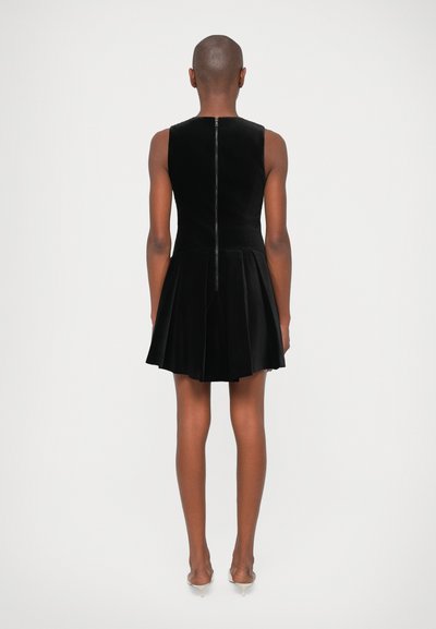 Zwarte fluwelen jurk met een getailleerde bovenkant en een uitlopende rok, voorzien van een ritssluiting aan de achterkant en zonder mouwen.