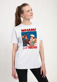 Bílé bavlněné tričko s grafikou obsahující text "WHAM!", barevný obrázek dvou postav v slavnostním oblečení a sněhové vločky v pozadí.