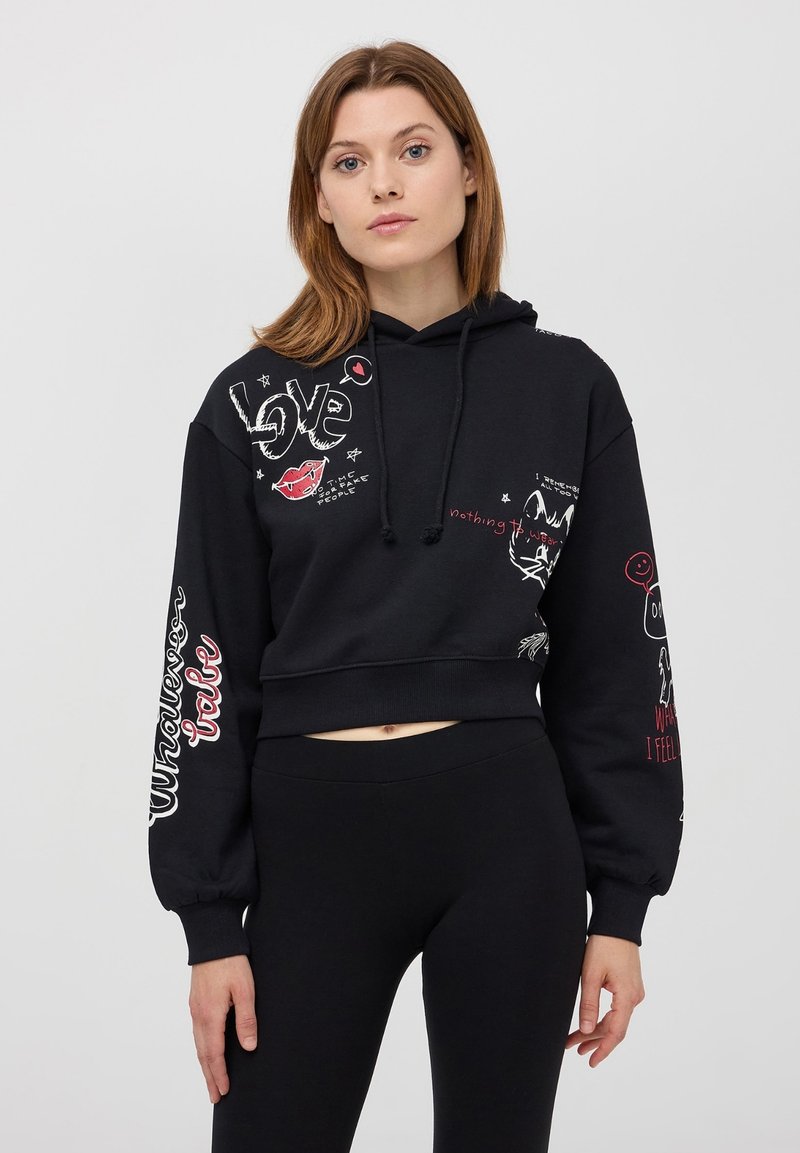 Cropped hoodie nera con cappuccio regolabile, caratterizzata da una stampa grafica che include la scritta "Love", illustrazioni di labbra e gatti in bianco e rosso. Tessuto morbido, vestibilità rilassata.